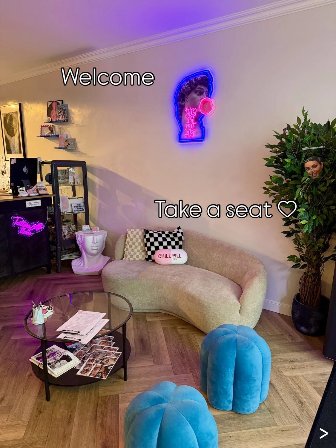 De comfortabele zithoek in de Venus Ink-studio, met Welcome en Take a seat op de foto